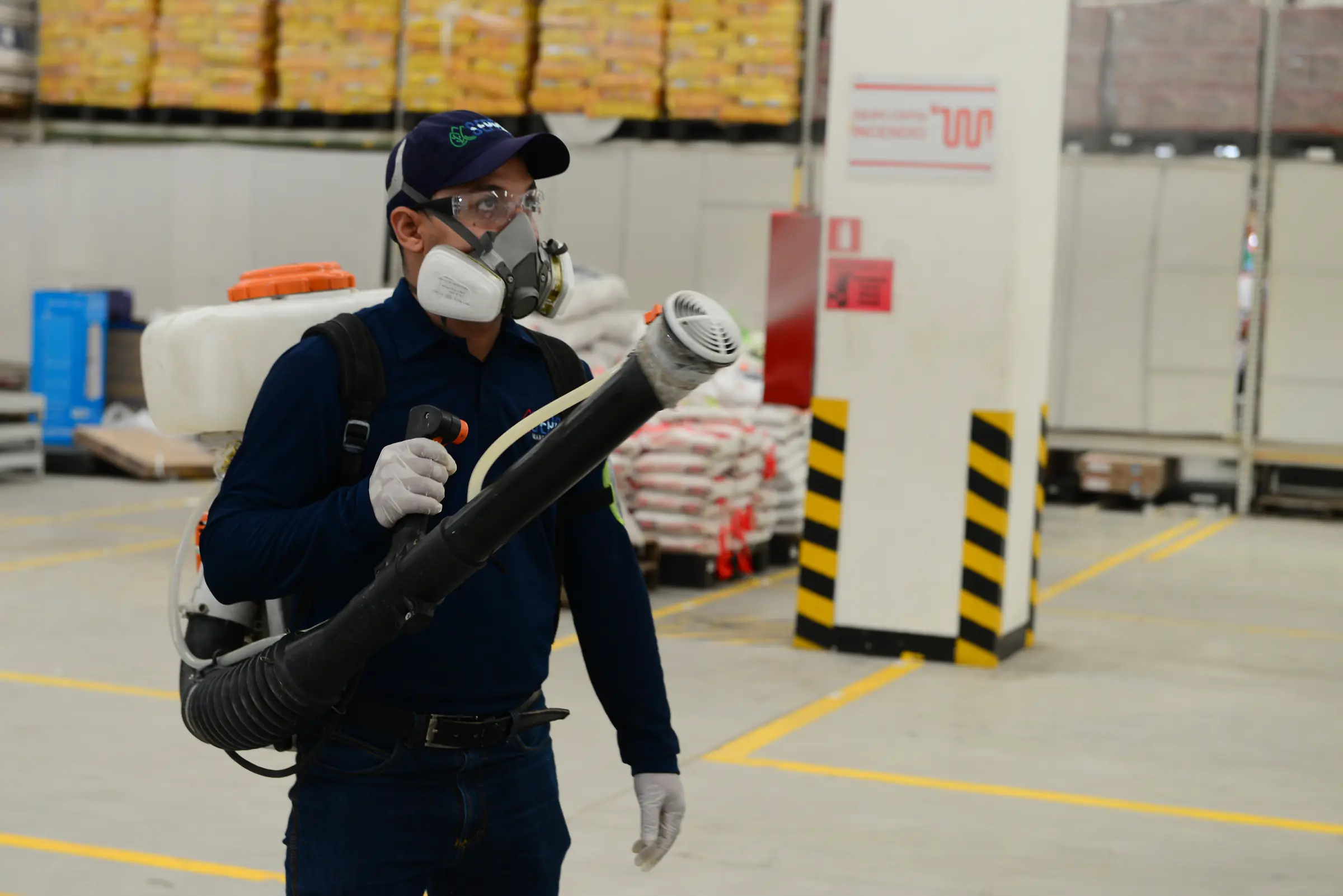 Técnico de SEPPSA aplicando control de plagas con termonebulizadora en una bodega industrial